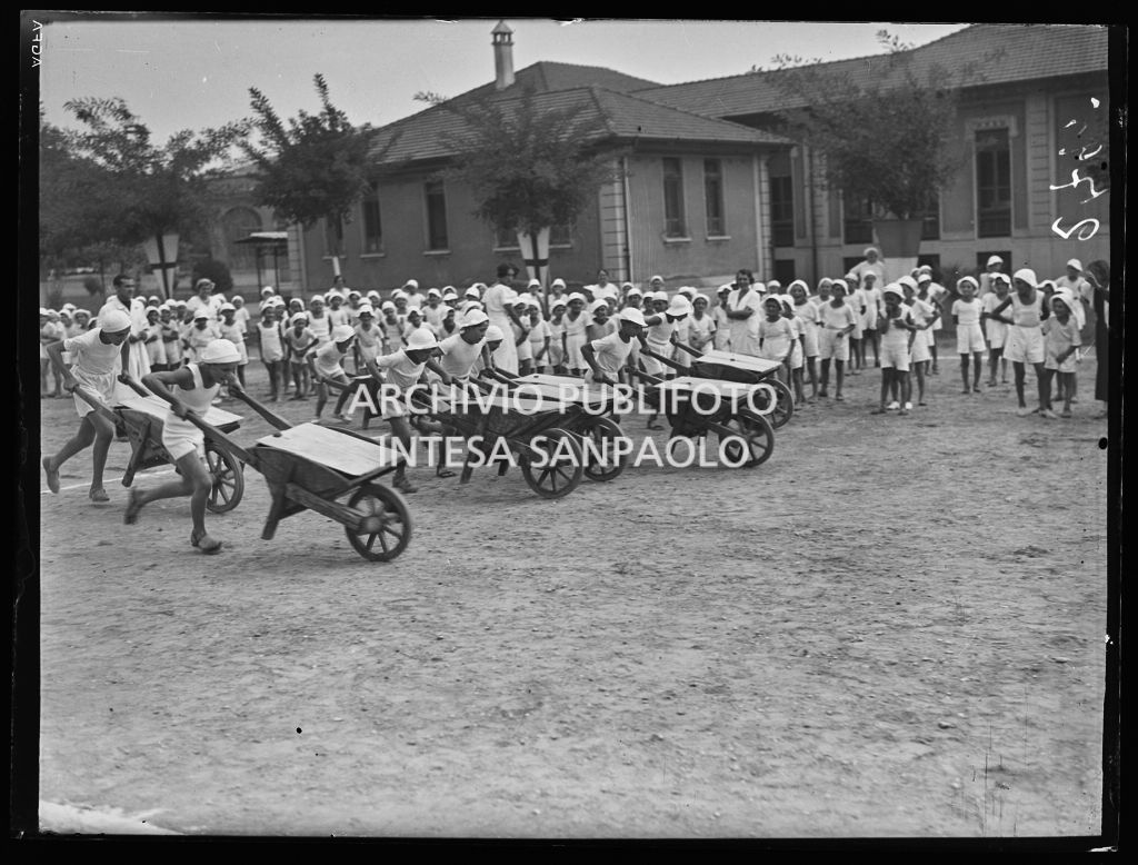 Bambini impegnati in una gara con le carriole nella colonia elioterapica del Parco Trotter a Milano