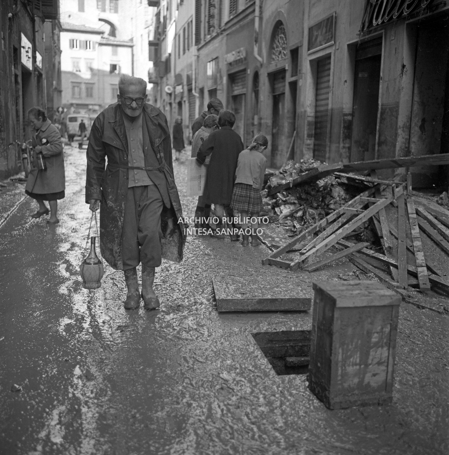 Un anziano trasporta dell'acqua in una via di Firenze dopo lo straripamento del fiume Arno