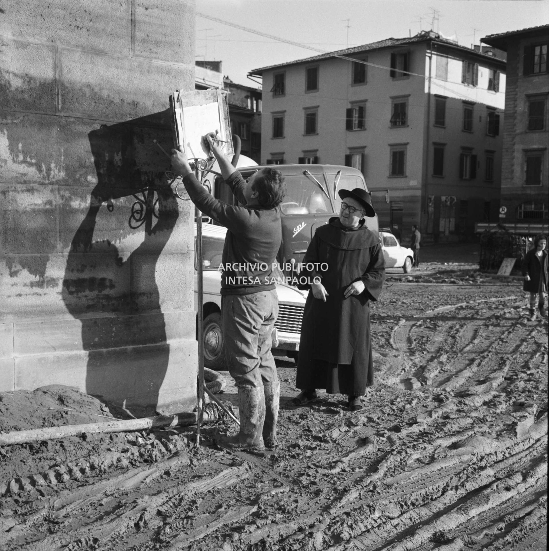 Alluvione di Firenze: un uomo scrive su un cartello che affigge in una via della città invasa dal fango