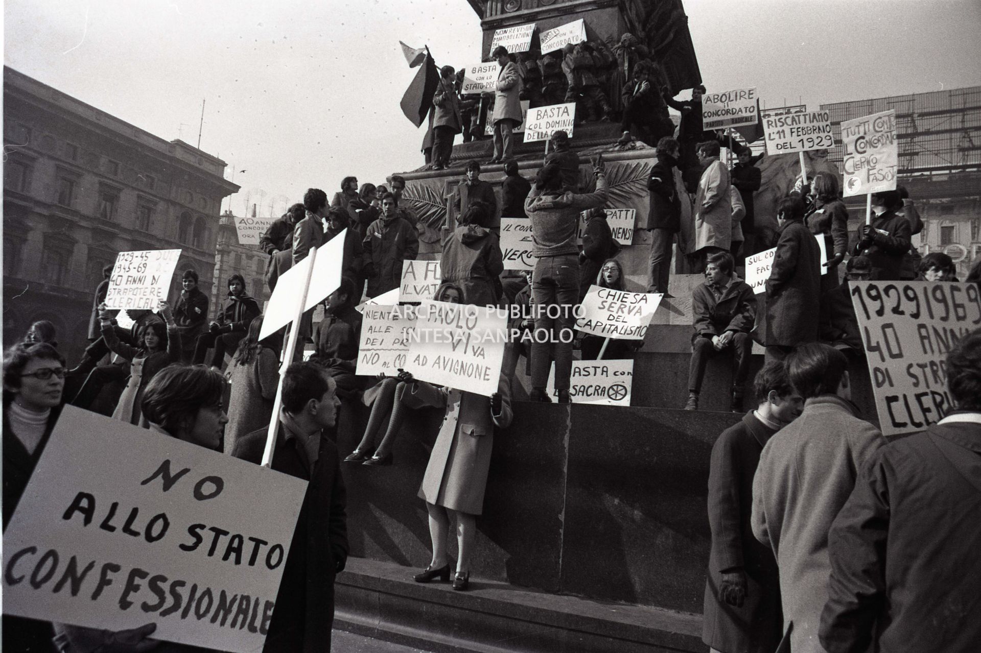 Studenti, con cartelli di protesta contro il Concordato Stato/Chiesa, sul monumento a Vittorio Emanuele II, in piazza del Duomo a Milano, in occasione del quarantesimo anniversario dei Patti Lateranensi