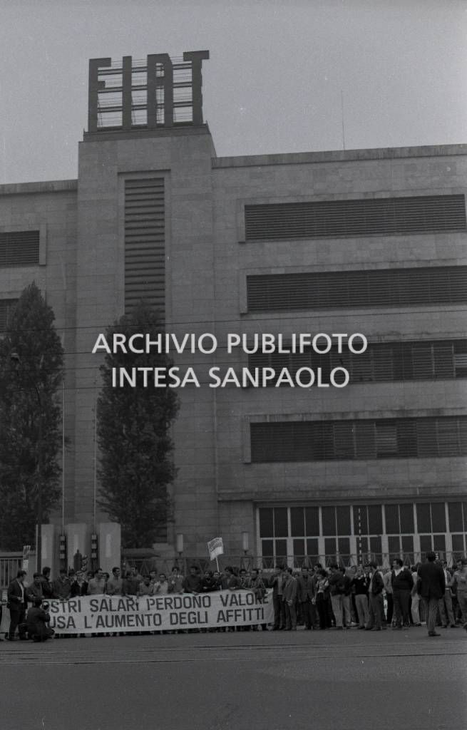 Operai in sciopero, davanti allo stabilimento Fiat Mirafiori, in corso Traiano a Torino; sullo striscione la scritta "I nostri salari perdono valore a causa dell'aumento degli affitti"
			Operai in sciopero<br>731931/46
