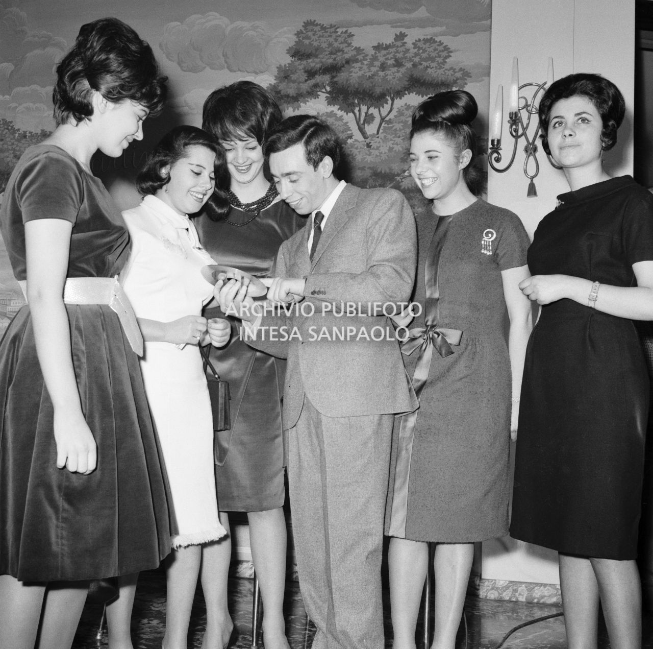 Umberto Bindi, circondato da numerose donne ammira il Disco d'Oro appena ricevuto<br>696394