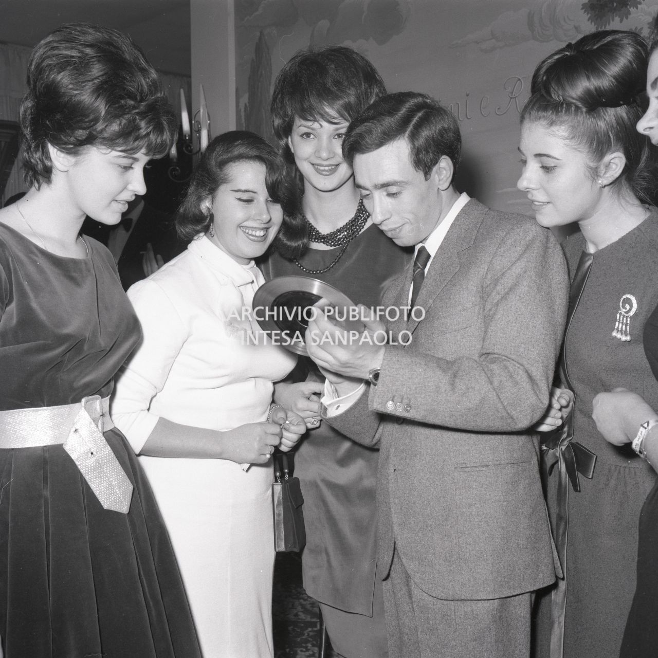 Umberto Bindi, circondato da numerose donne ammira il Disco d'Oro appena ricevuto<br>696396