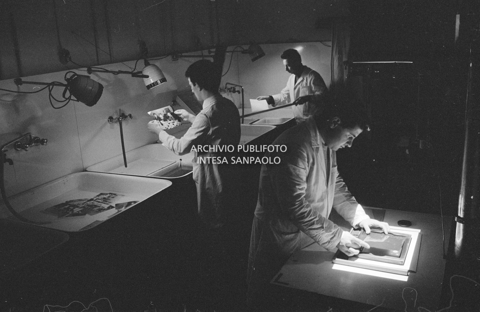 Addetti al lavoro nel laboratorio con camera oscura nella sede dell'agenzia Publifoto in via Bramante a Milano
