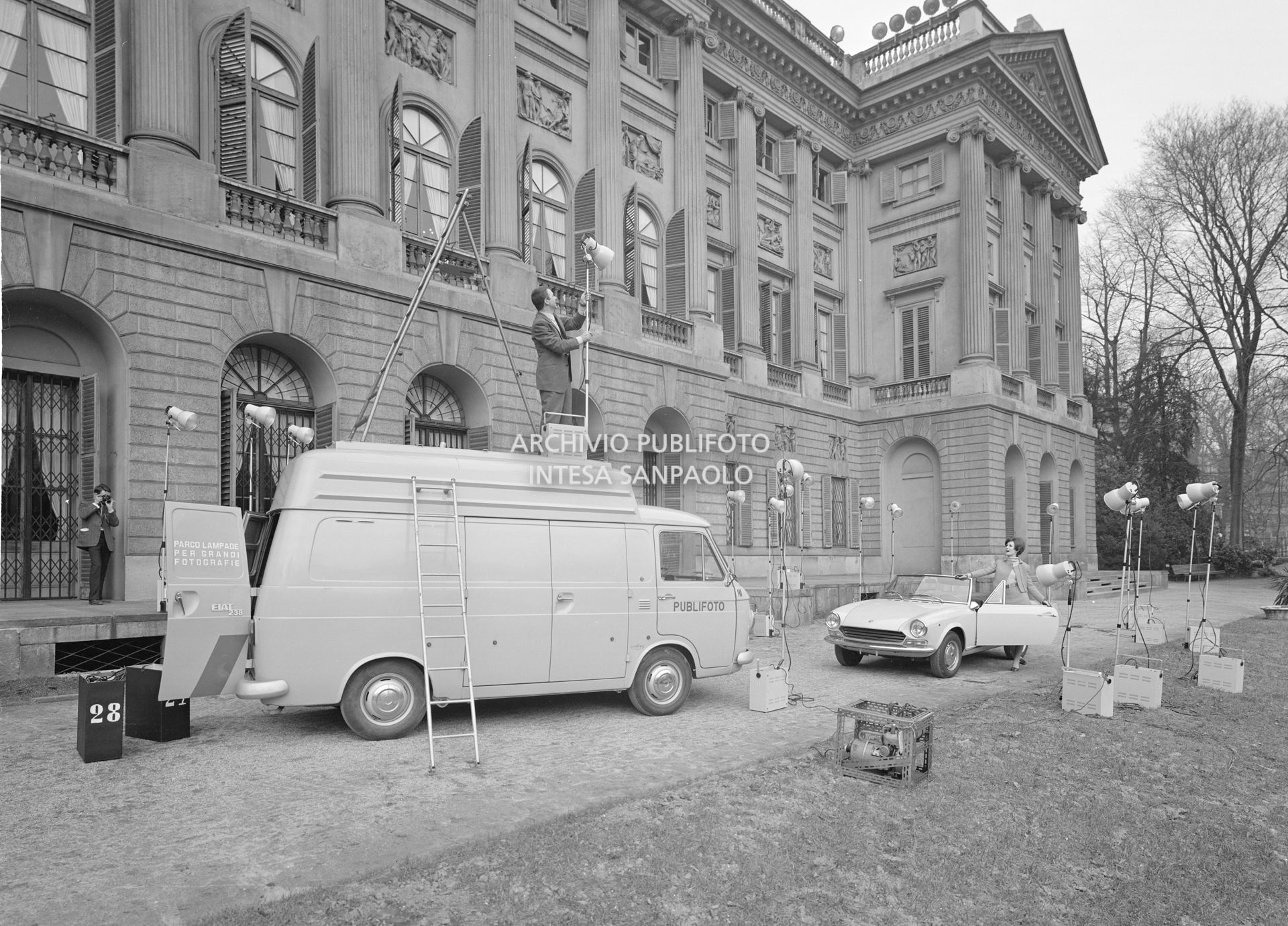 Set fotografico, dell'agenzia Publifoto, allestito nel giardino di Villa Reale a Milano: una modella ripresa accanto a una Fiat 124 Sport Spider
