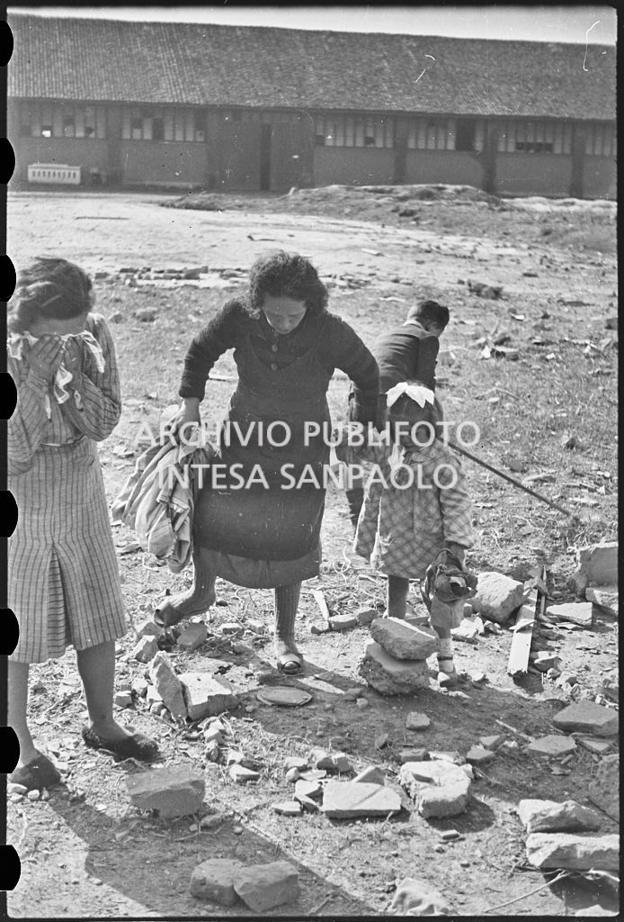 Due donne tra le macerie dei bombardamenti: una tiene per mano una bambina l'altra piange, sullo sfondo un ragazzino<br>26648