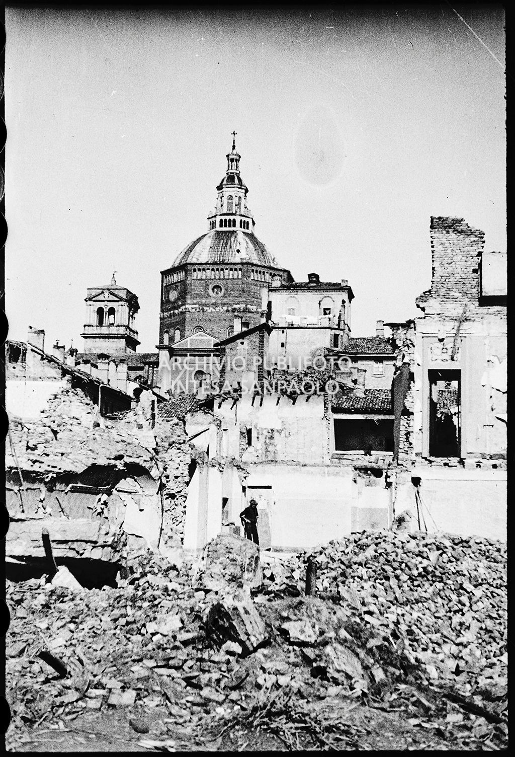 Un uomo cammina sulle macerie  bombardamenti a Pavia; sullo sfondo il Duomo della città intitolato a Santo Stefano protomartire e Santa Maria Assunta<br>26655