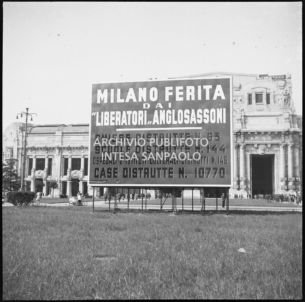 Grande cartello, posto davanti alla stazione Centrale di Milano, che elencava le distruzioni causate alla città dagli attacchi aerei dei "liberatori anglosassoni". Sullo sfondo la stazione.<br>26660