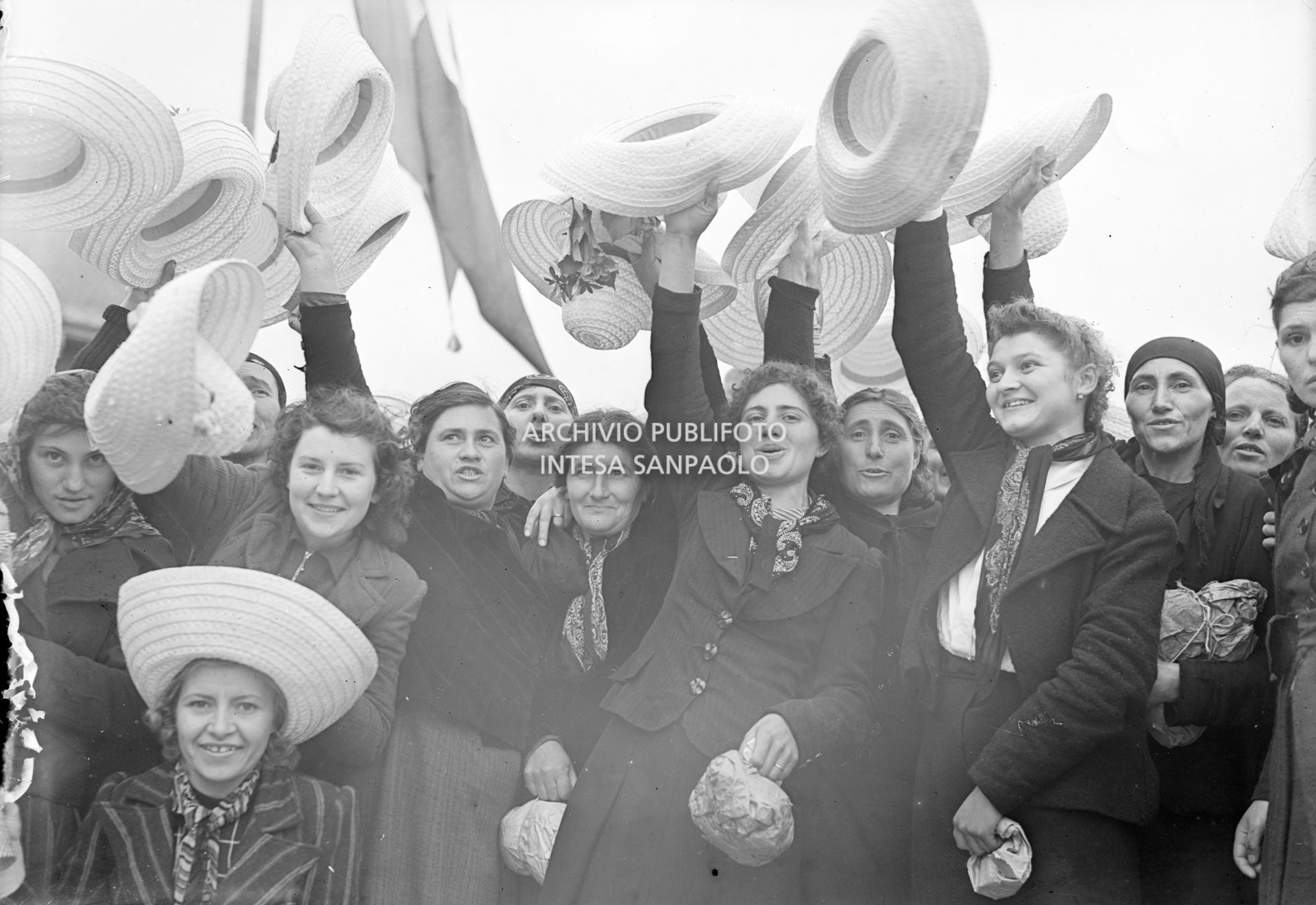 Foto di gruppo di mondine che salutano sventolando il cappello