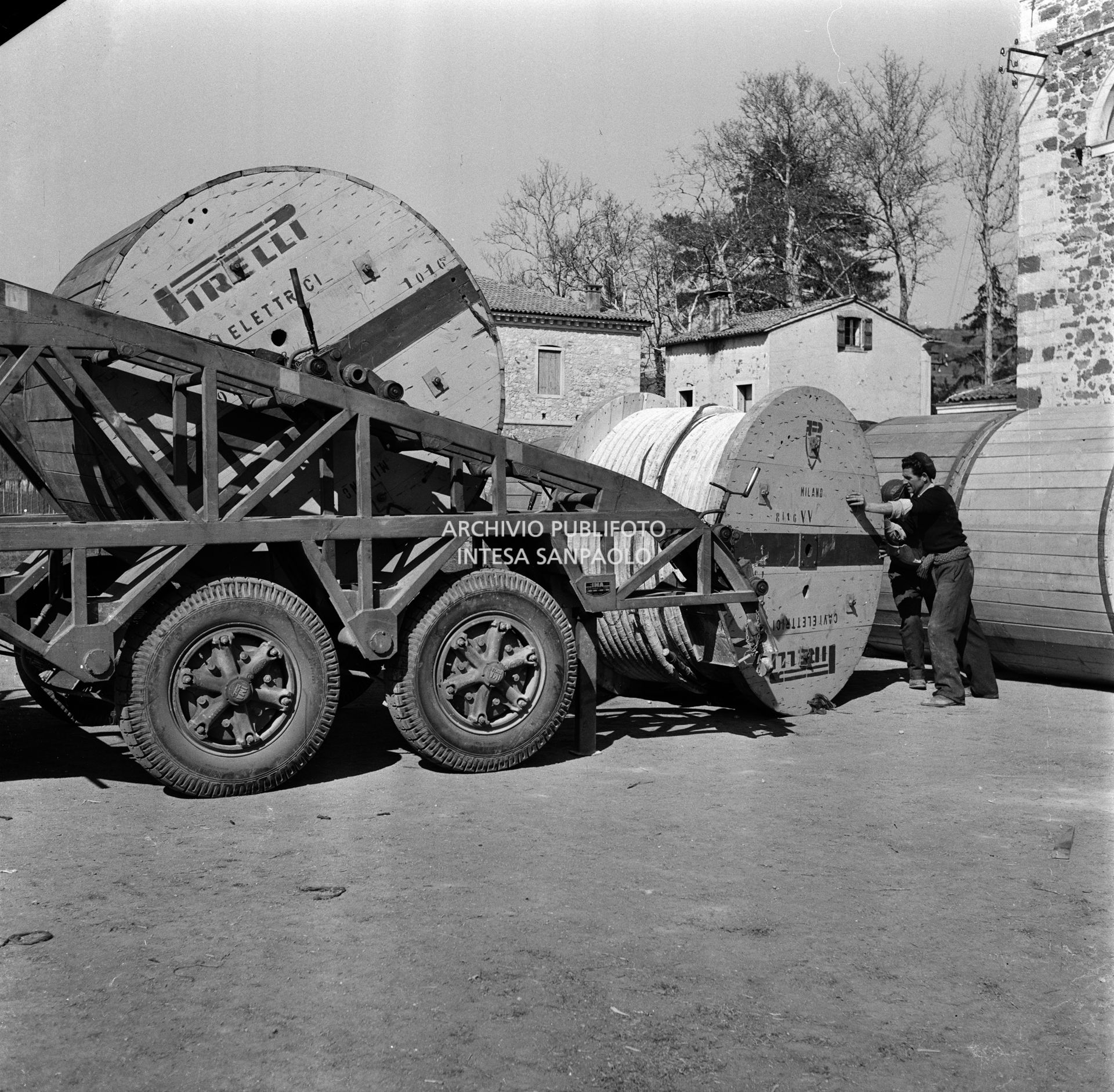 Bobine di cavi elettrici Pirelli movimentati da operai della SIRTI (Società Italiana Reti Telefoniche Interurbane) che stanno realizzando l'impianto di cavi coassiali nella provincia di Verona