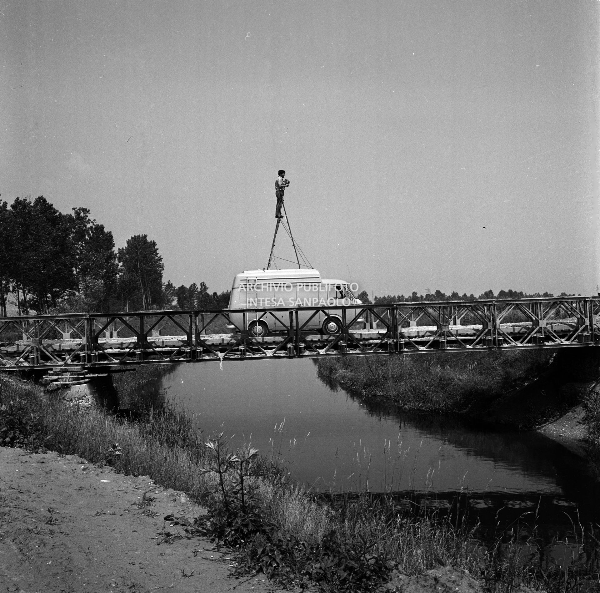 Set fotografico, dell'agenzia Publifoto, allestito in esterno: il fotografo riprende da una scala montata sul tettuccio del furgone Fiat 238 dell'agenzia