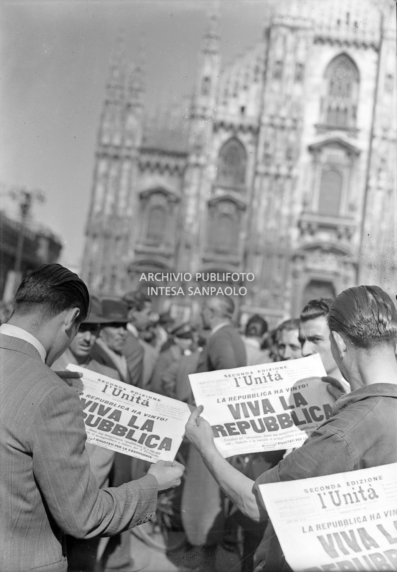 Folla in piazza del Duomo a Milano legge la seconda edizione de L'Unità che titola "La Repubblica ha vinto! Viva la Repubblica"