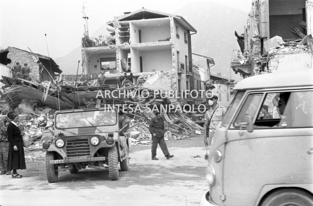 Passanti e automezzi, tra cui una jeep, si presume dell'esercito americano, in uno dei paesi del Friuli colpiti dal terremoto