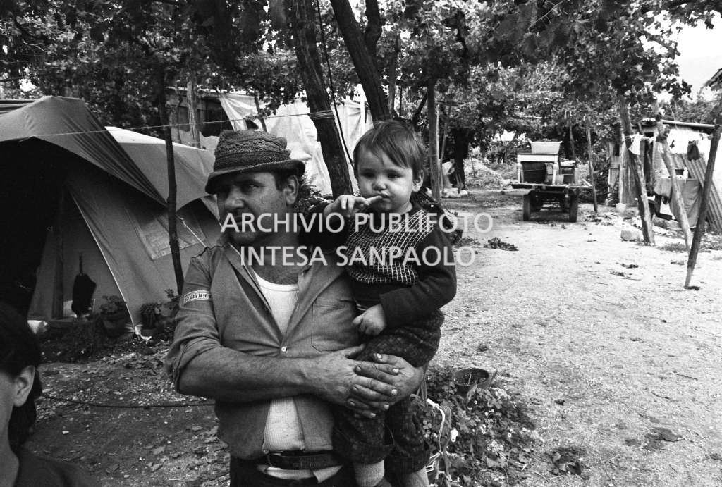 Un uomo ritratto con un bambino, alle loro spalle è visibile una tenda