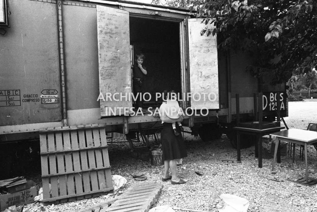 Una donna con due bambini vicino ad un vagone ferroviario in una delle città colpite dal terremoto del Friuli