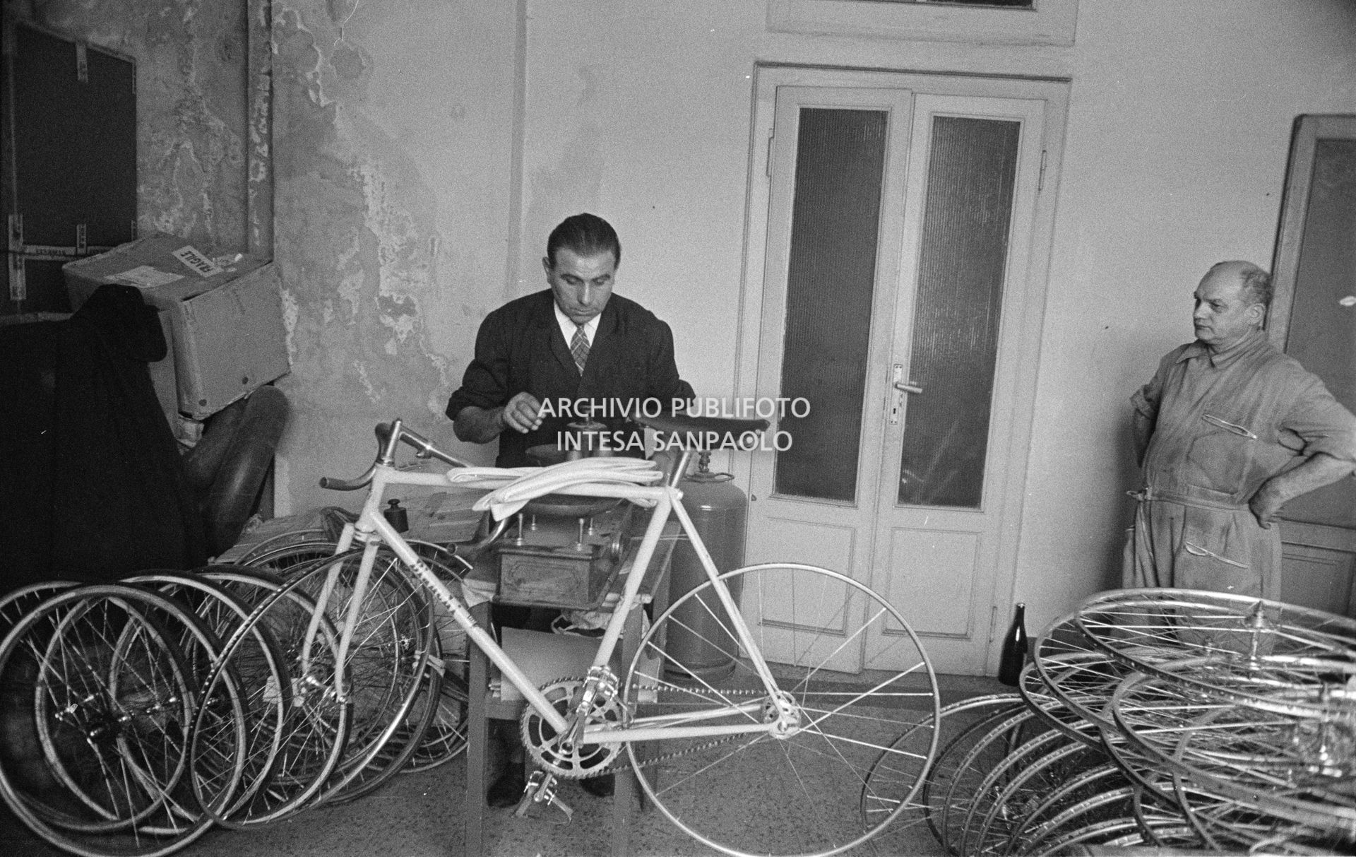 Il meccanico Giuseppe De Grandi, detto Pinella, pesa la bicicletta che sta preparando per Roger Rivière con la quale, di lì a tre giorni, il ciclista francese si sarebbe aggiudicato il record dell'ora