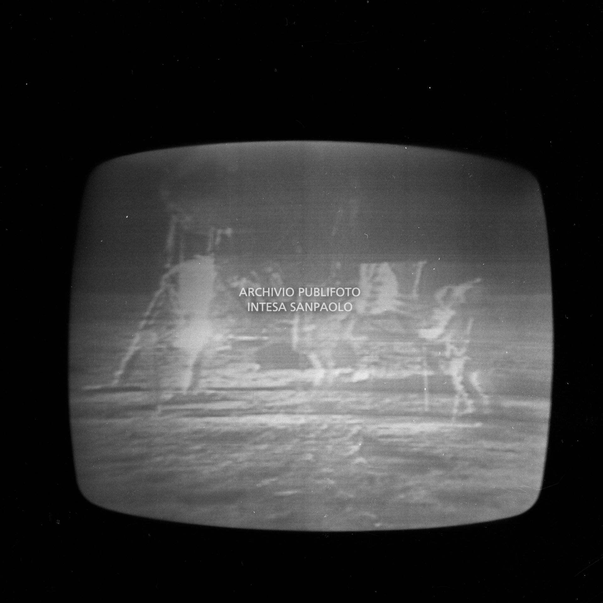 Ripresa dello schermo televisivo che trasmette la storica diretta  dello sbarco sulla luna, durata 28 ore, e condotta dallo studio 3 della RAI di via Teulada a Roma qui in collegamento con lo studio di Milano: nell'immagine i primi passi sulla luna