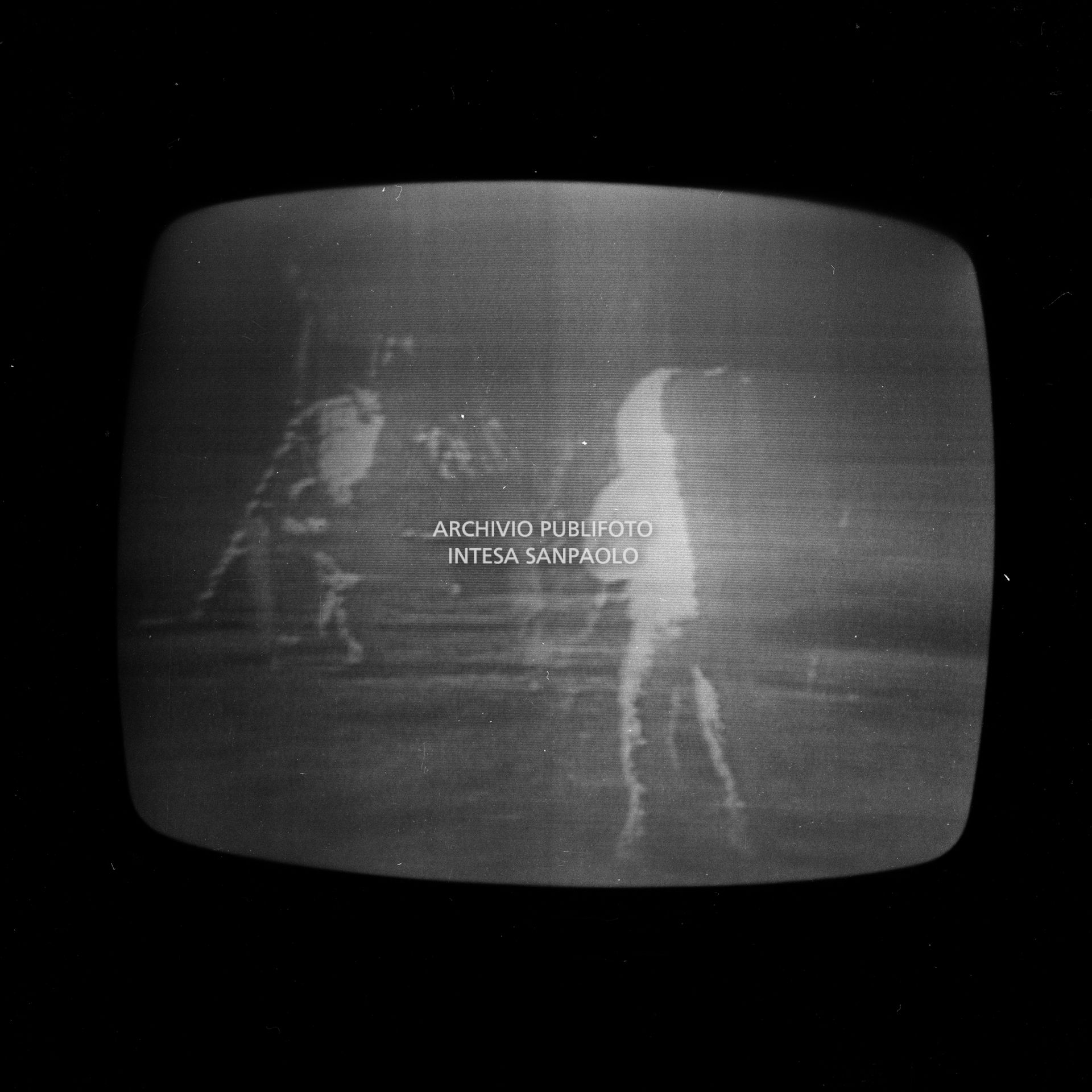 Ripresa dello schermo televisivo che trasmette la storica diretta  dello sbarco sulla luna, durata 28 ore, e condotta dallo studio 3 della RAI di via Teulada a Roma qui in collegamento con lo studio di Milano: nell'immagine i primi passi sulla luna