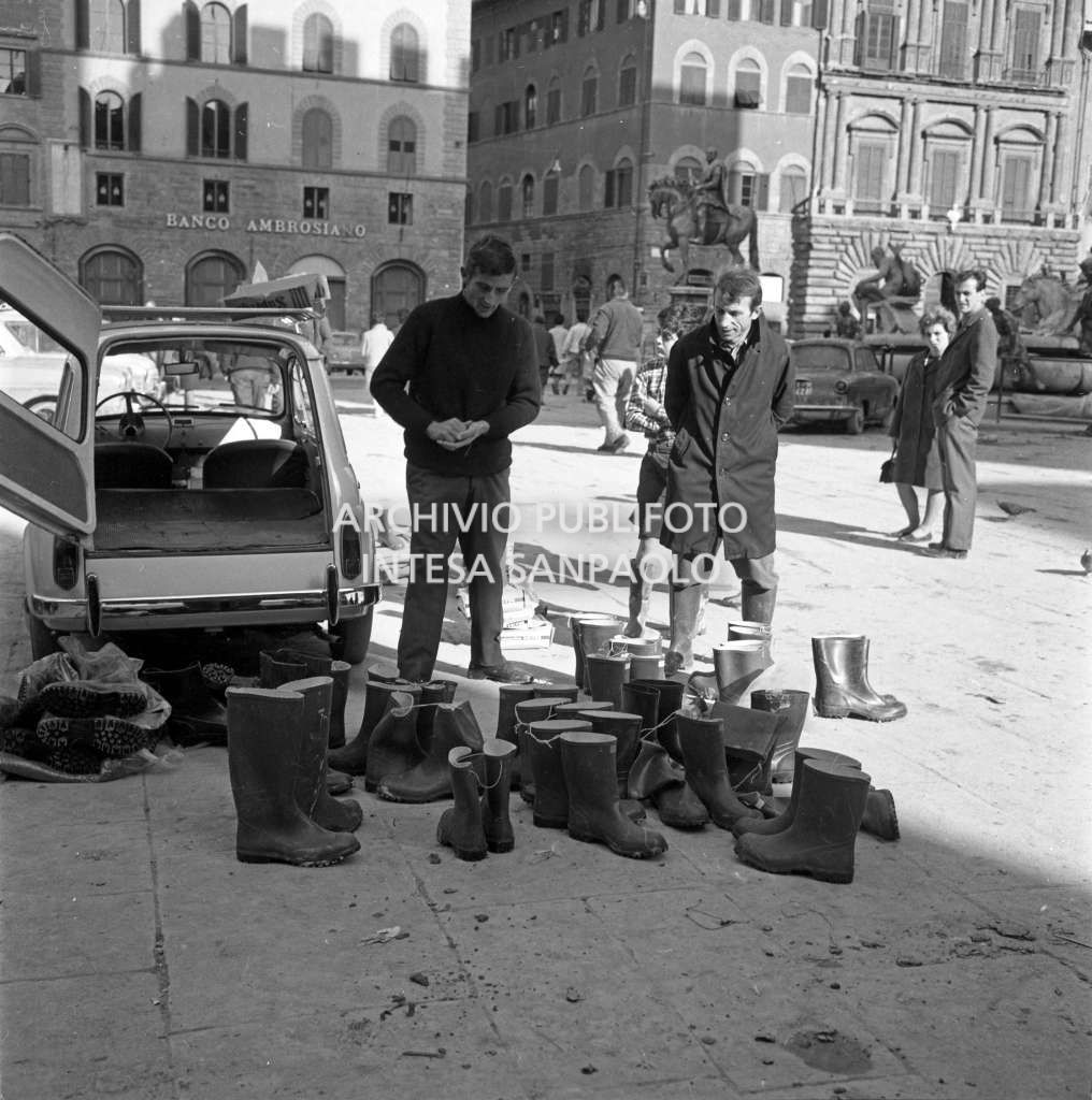 Un uomo vende stivali di plastica in piazza della Signoria a Firenze dopo lo straripamento del fiume Arno