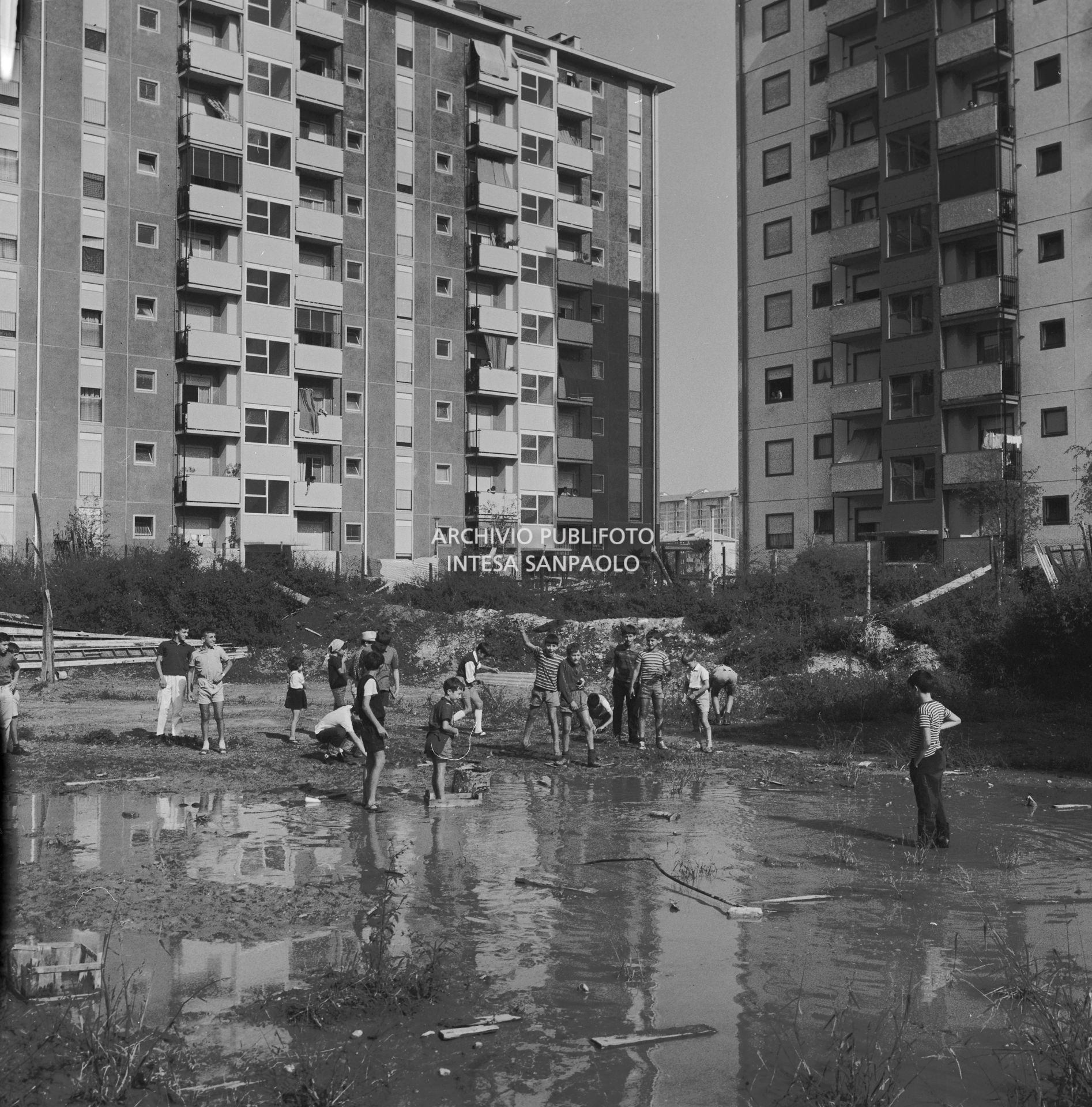 Un gruppo di bambini gioca in un campo semi allagato nel nuovo quartiere Gallaratese