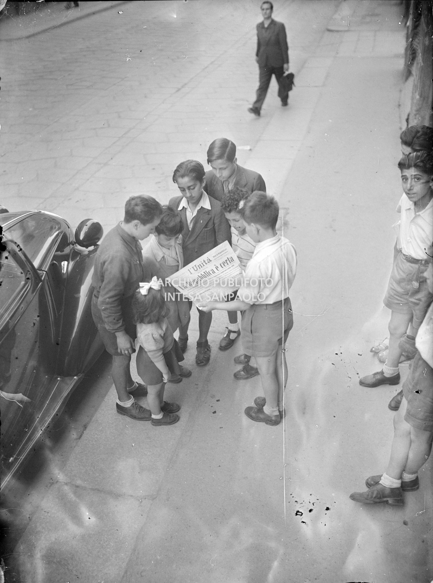 Ragazzini per strada tengono in mano il quotidiano L'Unità che titola: "La Repubblica è certa".