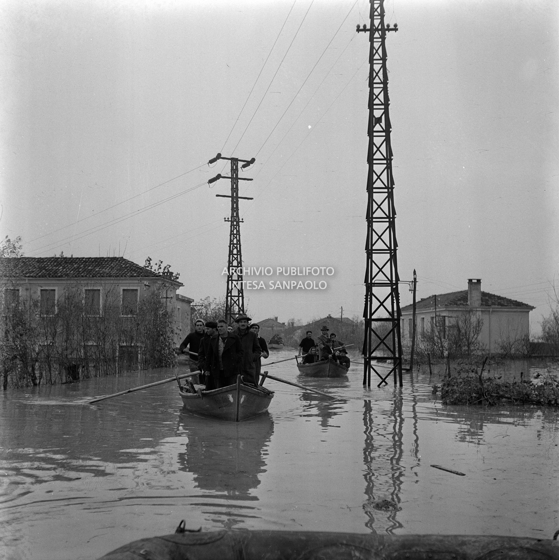 Due barche a remi, cariche di uomini, durante l'alluvione nelle campagne del Polesine