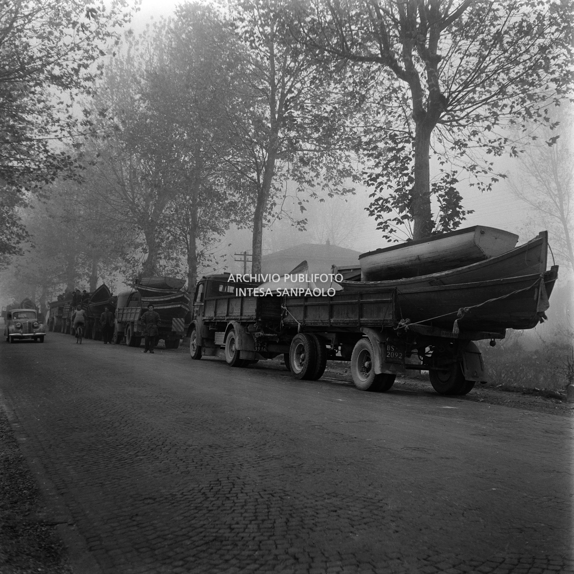 Colonna di autocarri carichi di imbarcazioni a remi nei pressi di Rovigo durante l'alluvione del Polesine
