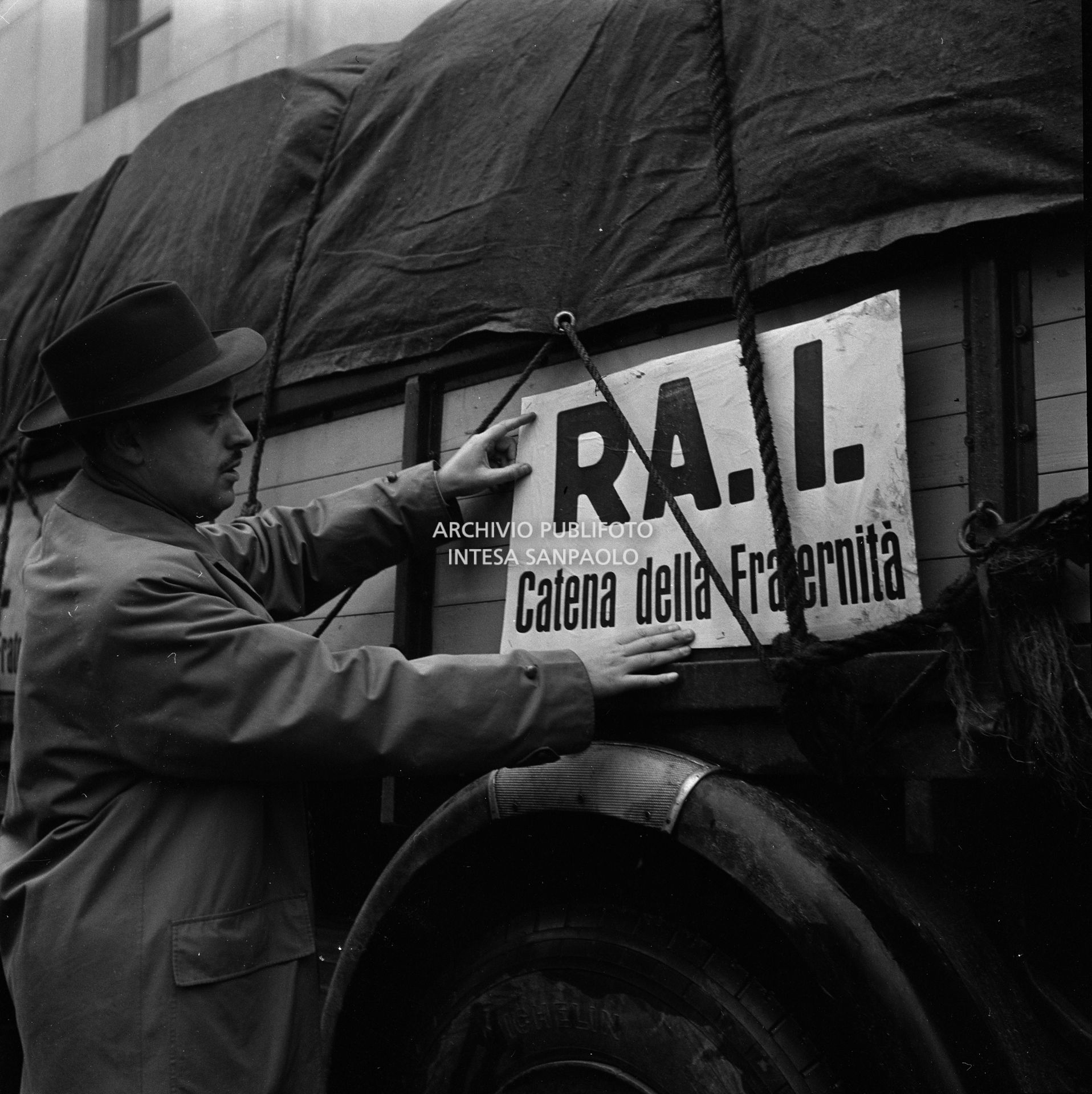 Affissione del cartello "RAI Catena della fraternità" a un autocarro della colonna della trasmissione radiofonica della RAI con la quale si promosse l'appello alla solidarietà agli alluvionati del Polesine, dalla sede RAI di corso Sempione a Milano