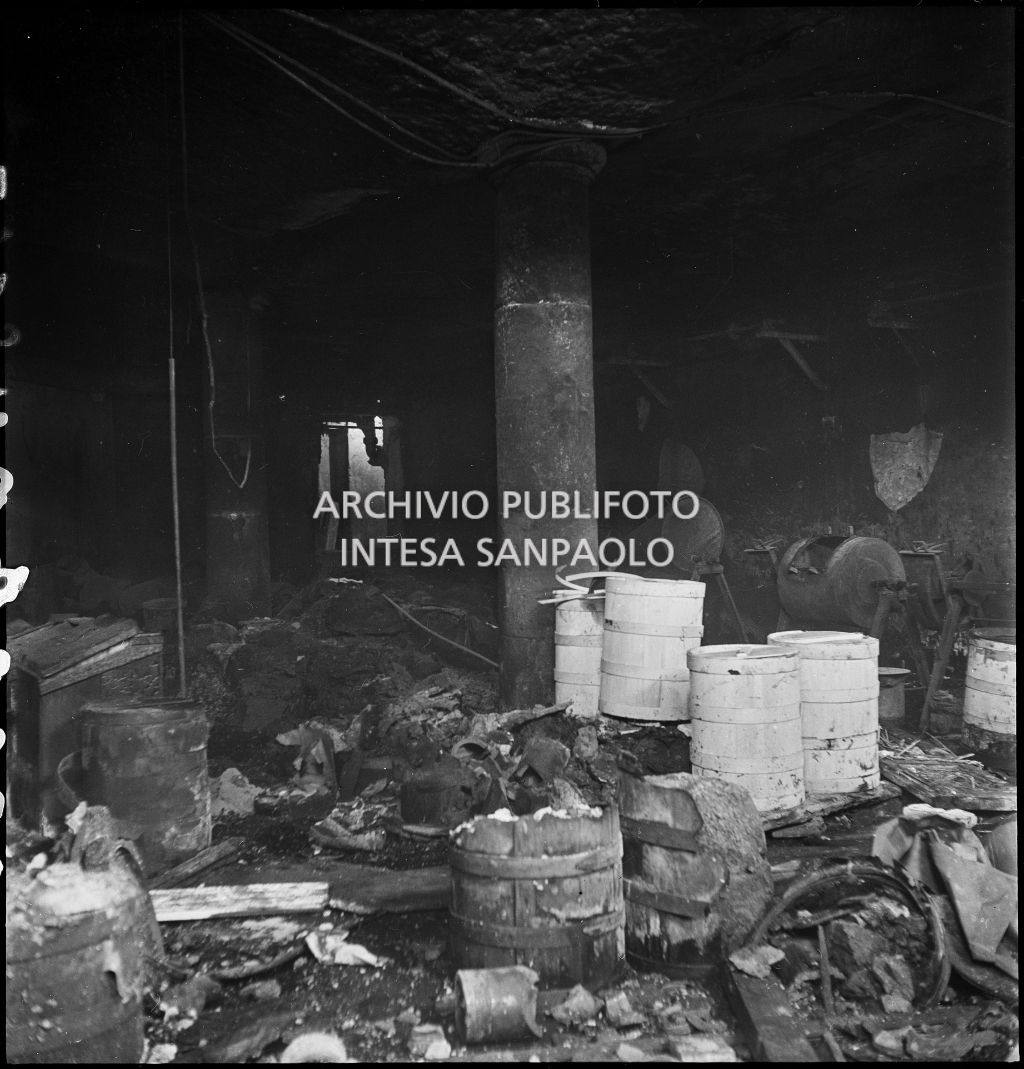 Interno di un locale, dell'impresa, presumibilmente la Accomandita «H» a Colori Anilina Visconti Gonella e C., in via Castelfidardo a Milano, bombardato e ingombro di macerie, bidoni e strumenti di lavoro