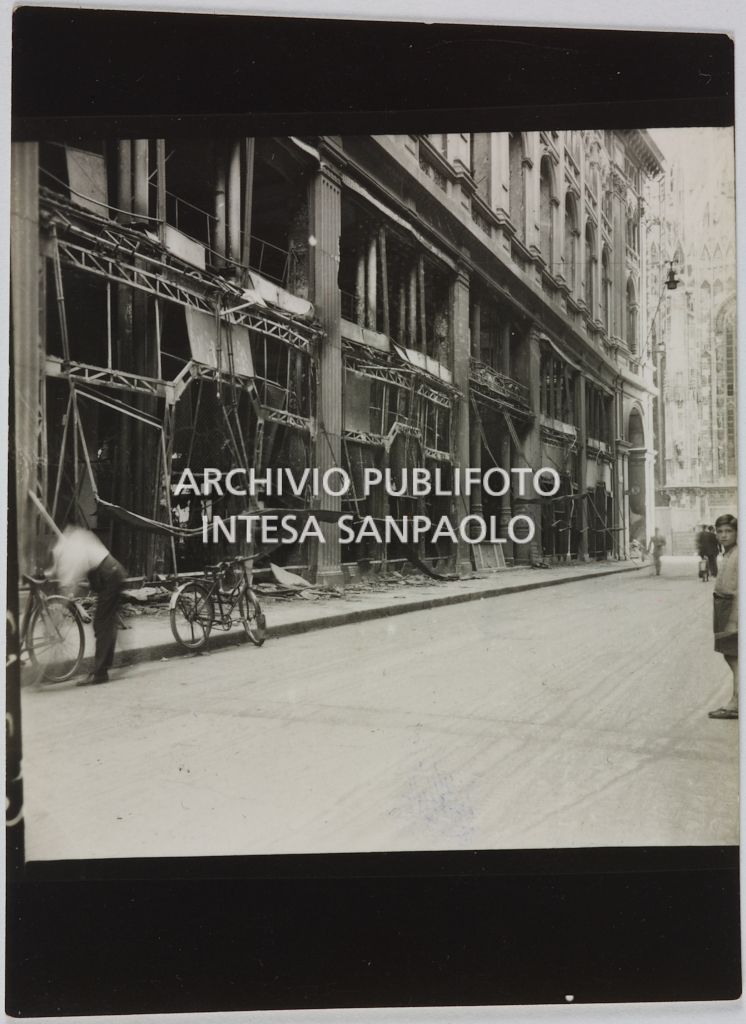 Scorcio dell'esterno del palazzo della Rinascente, dal lato di via San Raffaele a Milano, sventrato dai bombardamenti. Sullo sfondo si intravede il Duomo di Milano