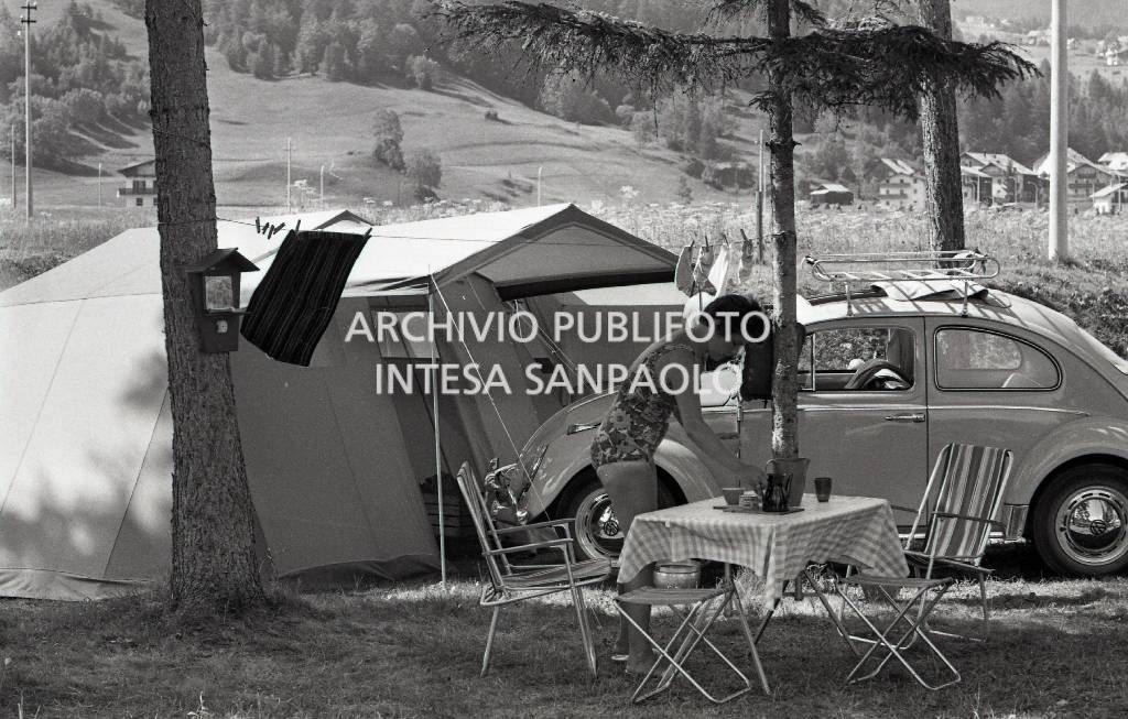 Turista in campeggio a Cortina d'Ampezzo tra tende a casetta e una Volkswagen Maggiolino<br>706765/31