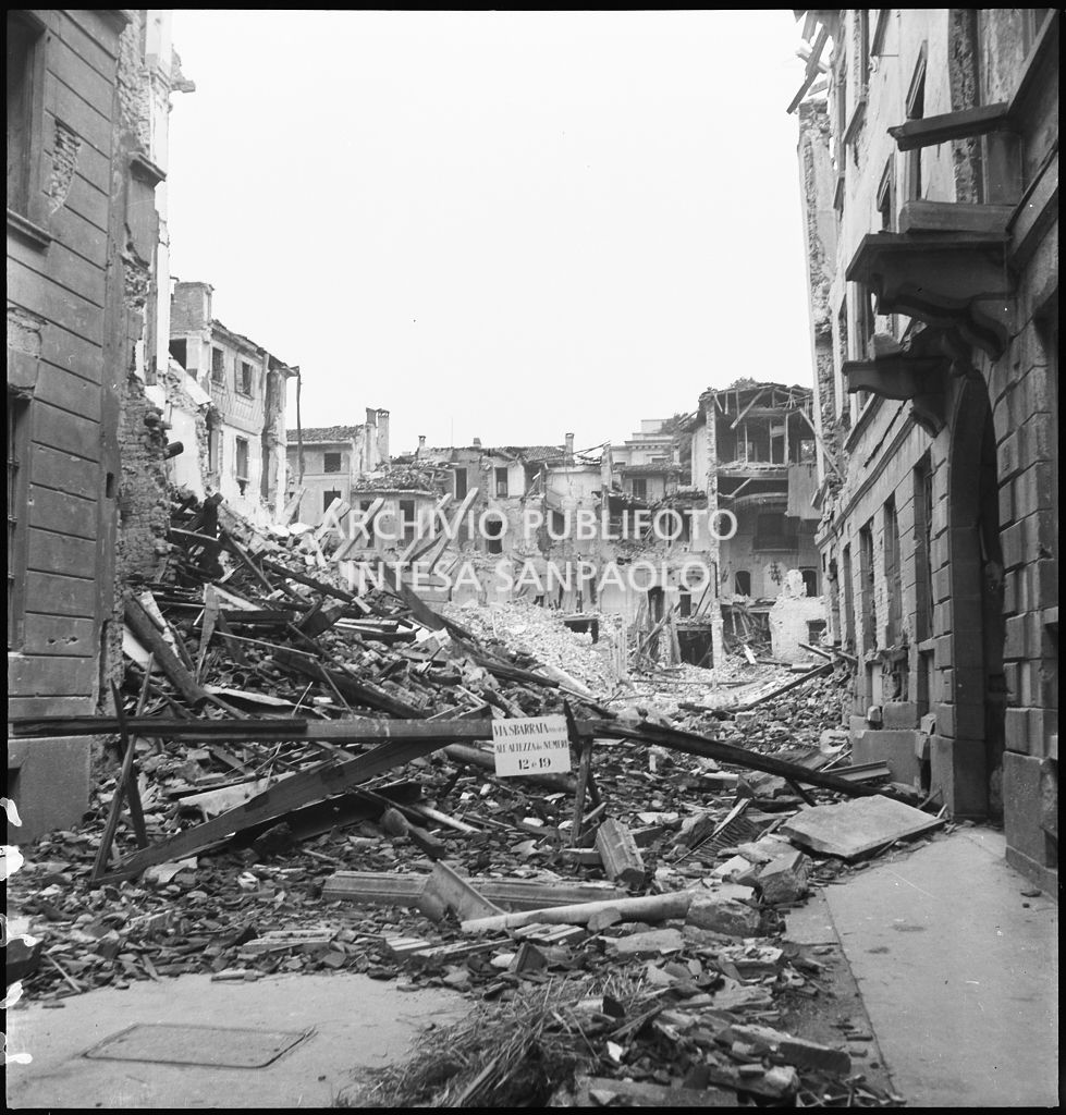 Edifici distrutti dai bombardamenti in via Gesù a Milano. Sulla sbarra il cartello: "via sbarrata (via Gesù) all'altezza dei numeri 12 e 19"