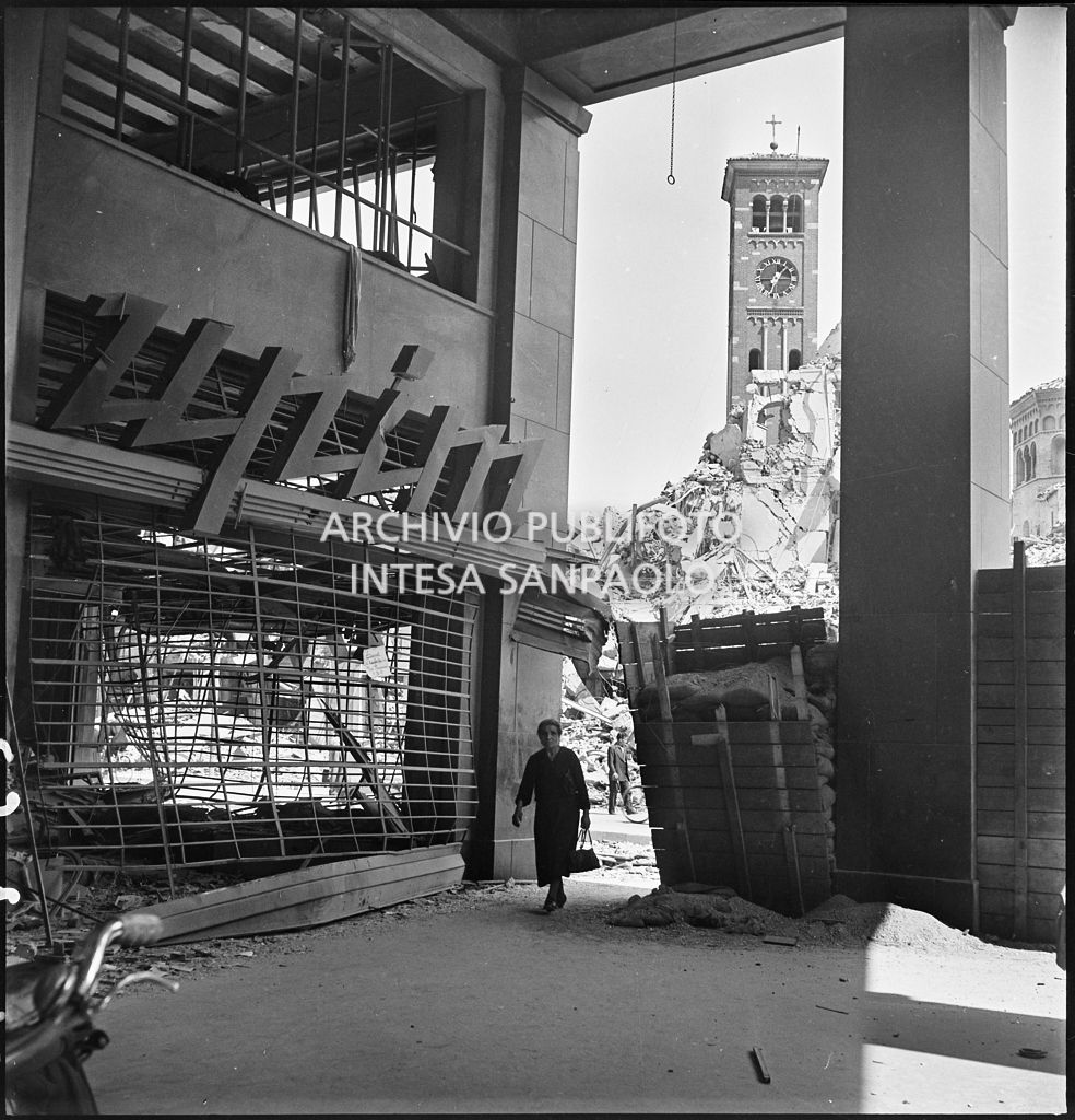 Una donna nell'area esterna all'ingresso del magazzino Upim in corso Venezia a Milano chiuso al passaggio con pannelli di legno dopo i bombardamenti che hanno gravemente danneggiato l'edificio e il negozio