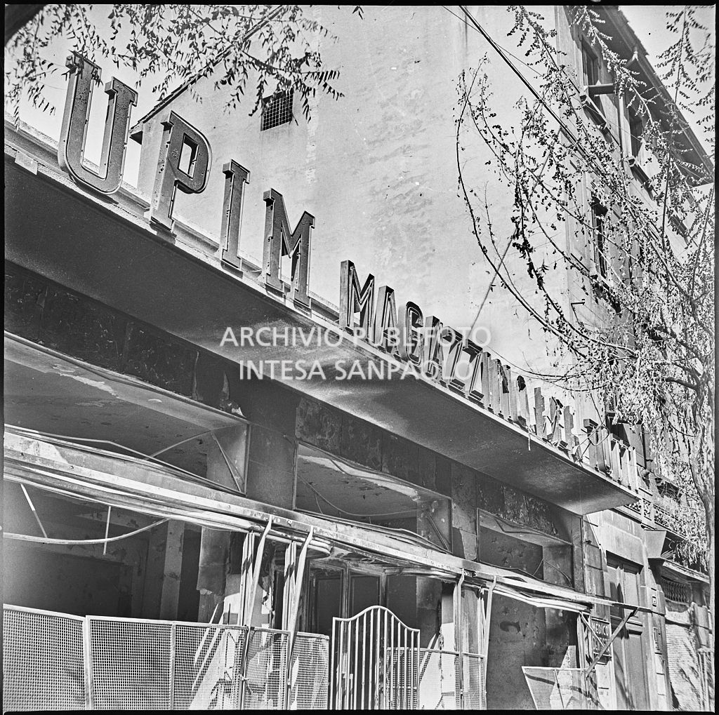 Scorcio dell'ingresso del magazzino Upim, in corso Ventidue Marzo, a Milano, gravemente danneggiato dai bombardamenti e dell'insegna: "Upim Magazzino per tutti"