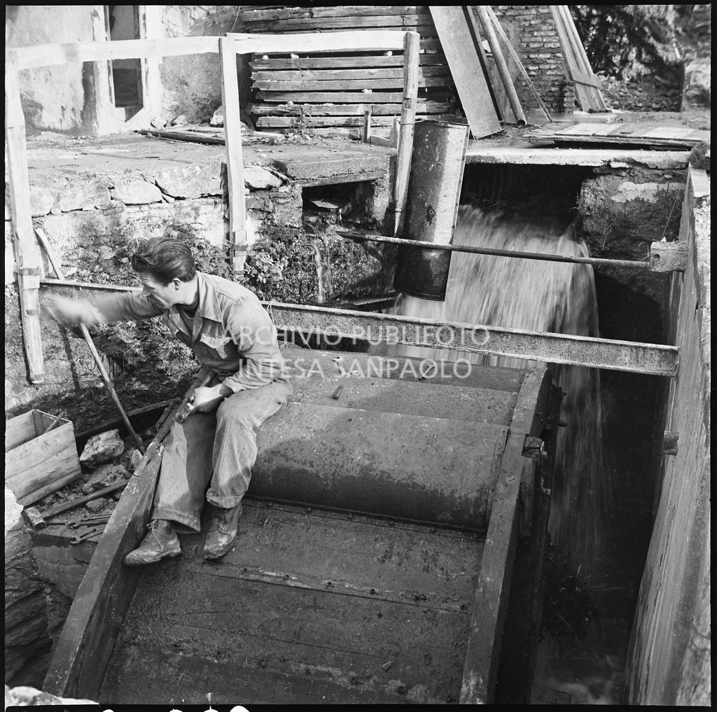 Un uomo seduto sulla ruota idraulica di un mulino presso lo stabilimento Belsana<br>26666