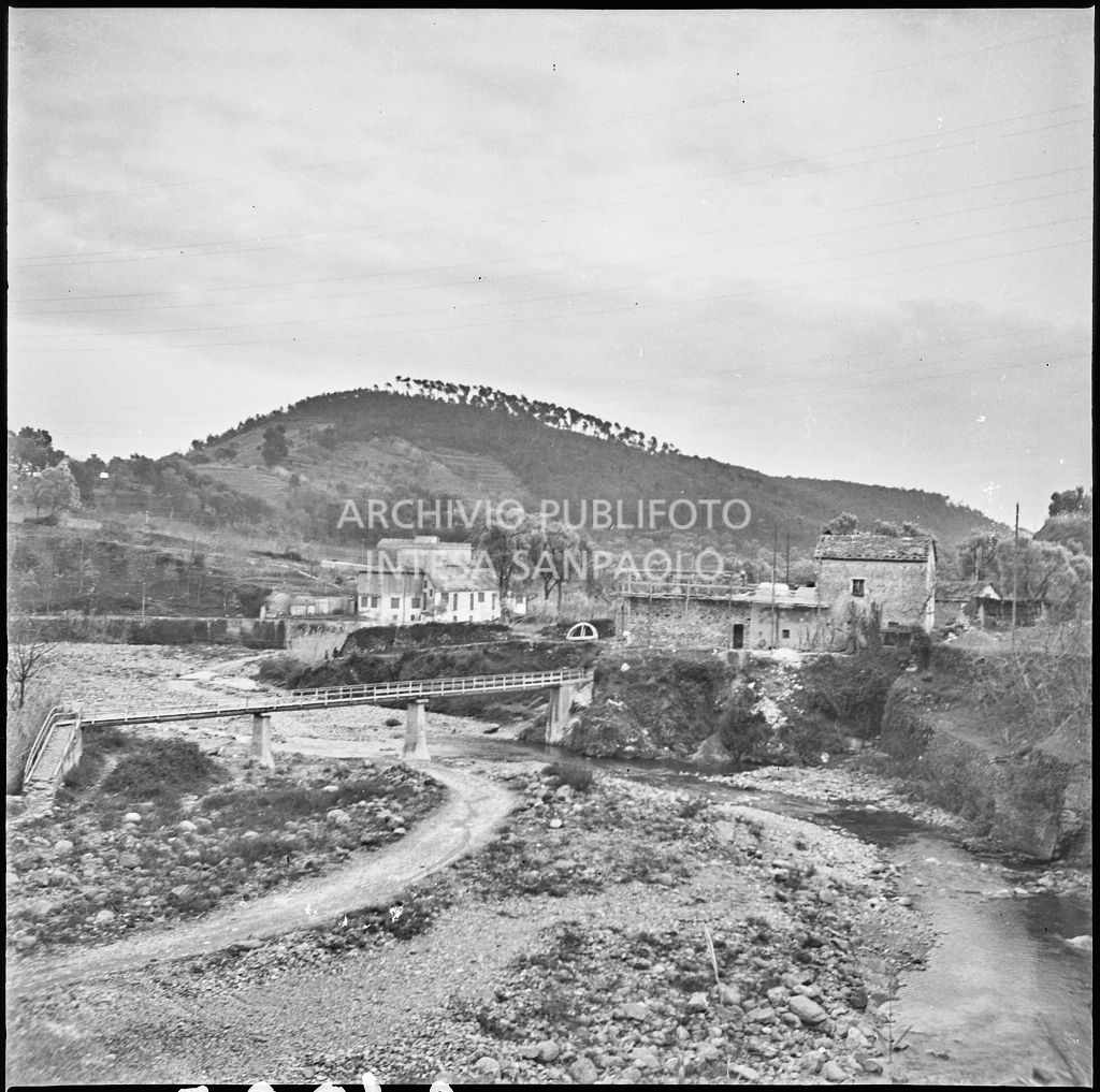 Veduta della valle percorsa da un torrente, attraversato da un ponte, dove è situato lo stabilimento Belsana<br>26673