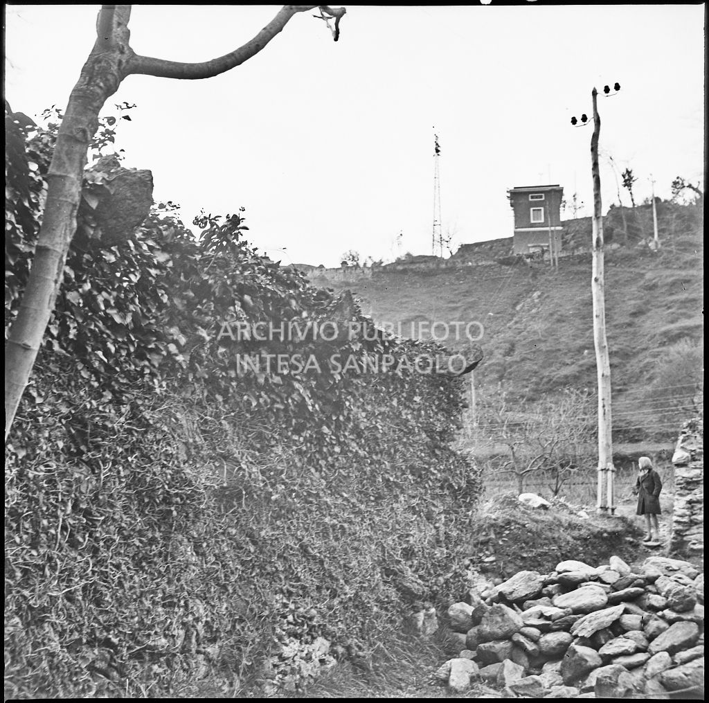 Particolare di un muro danneggiato dai bombardamenti nei pressi dello stabilimento Belsana; sullo sfondo una donna<br>26706