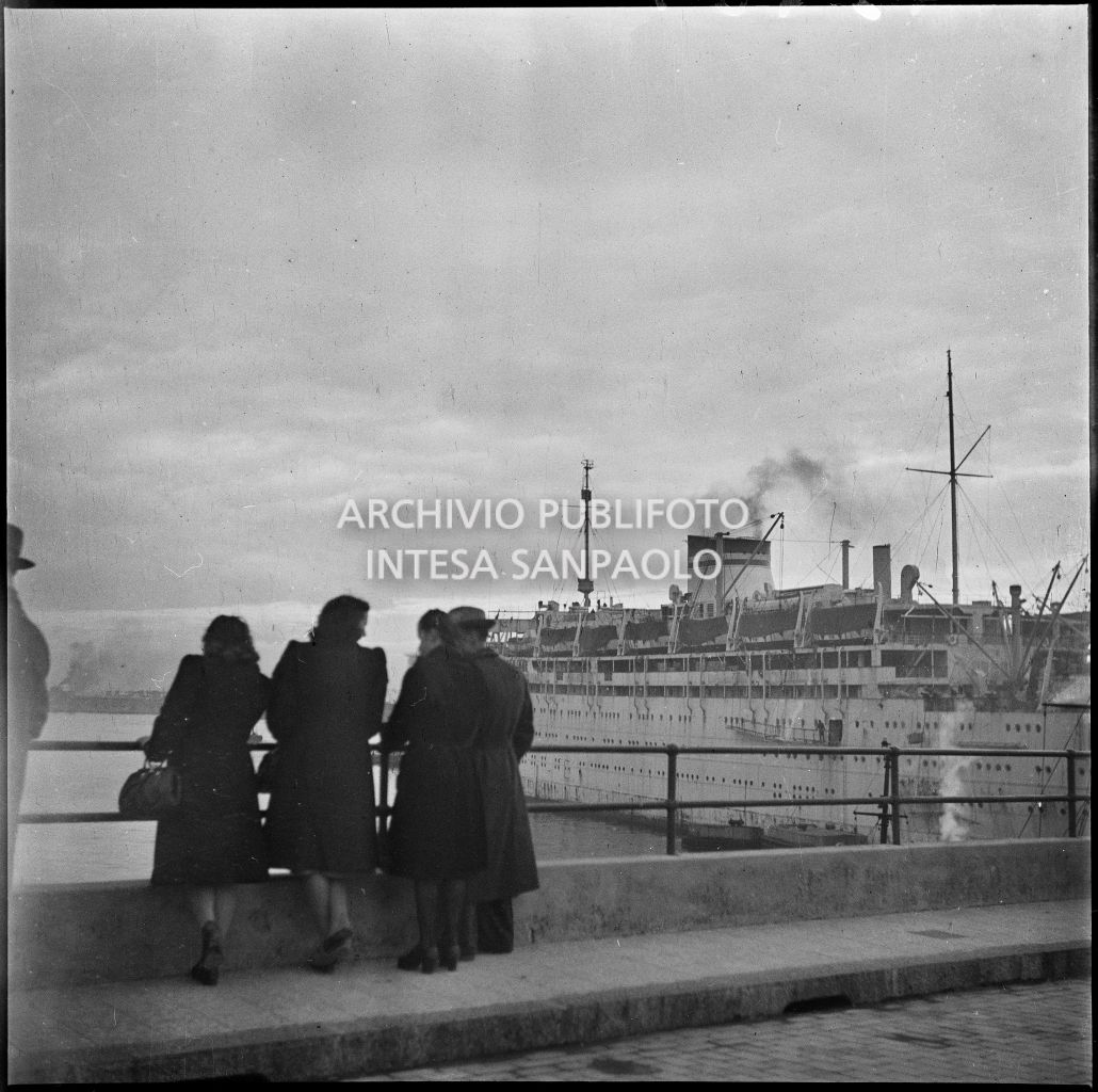 Alcune persone al porto di Genova guardano una nave passeggeri ormeggiata<br>23285