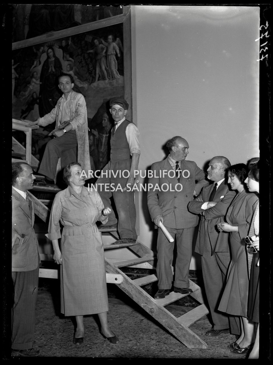 La direttrice della Pinacoteca di Brera Fernanda Wittgens assiste ai lavori di restauro delle opere con il restauratore Mauro Pellicioli, sulla scala con camice, e l'architetto Piero Portaluppi, terzo da destra, autore della ricostruzione della Pinacoteca, in vista dell'imminente riapertura<br>73175