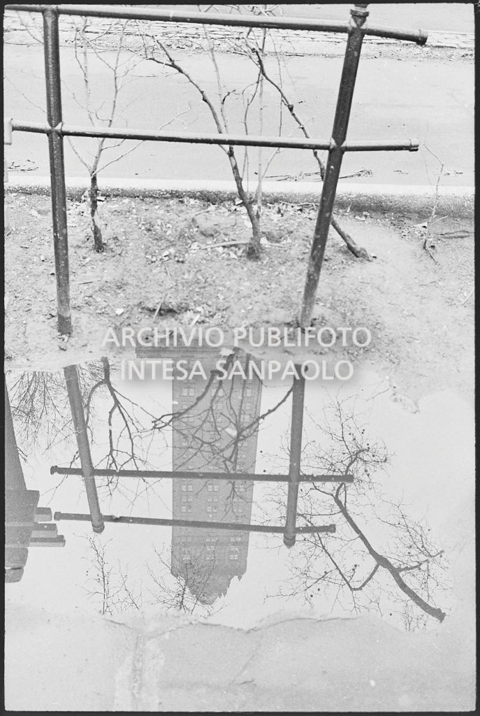 Riflesso di un grattacielo di New York in una pozzanghera il giorno della marcia contro la guerra in Vietnam promossa dallo Spring Mobilization Committee