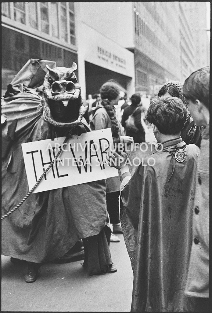 Un dimostrante, in mezzo ad altri, travestito da drago, con il cartello "The war", sfila per le strade di New York in occasione della marcia contro la guerra in Vietnam promossa dallo Spring Mobilization Committee