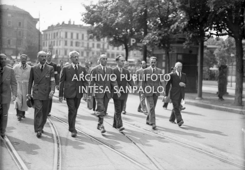 Mario Argenton, Giovan Battista Stucchi, Ferruccio Parri, il generale Raffaele Cadorna, Luigi Longo, Enrico Mattei e Fermo Solari sfilano a Milano, in piazza Castello, insieme alle formazioni partigiane