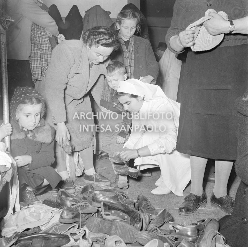 Un'infermiera della Croce Rossa, alla Stazione Centrale di Milano, distribuisce scarpe agli sfollati del Polesine