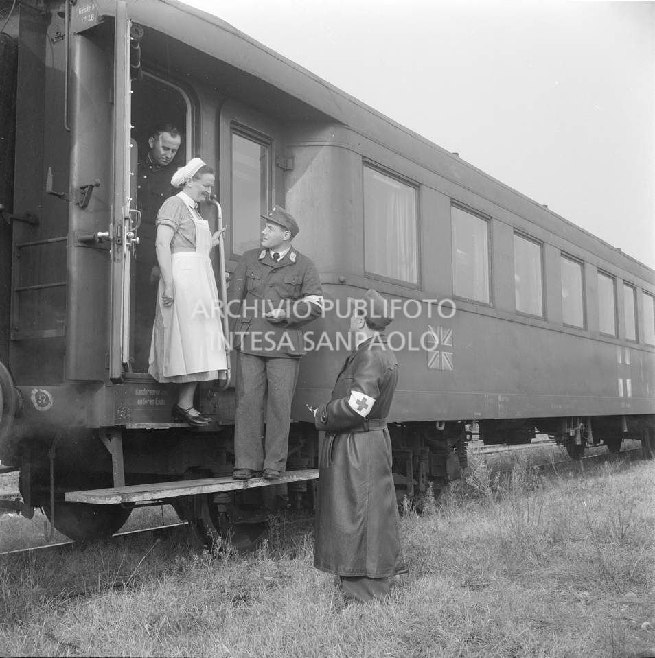 Militari discorrono con un infermiera sui gradini di un treno ospedale, sulla cui fiancata è affissa la bandiera del Regno Unito, inviato in soccorso agli alluvionati del Polesine, a Pontelagoscuro, frazione di Ferrara<br>113906