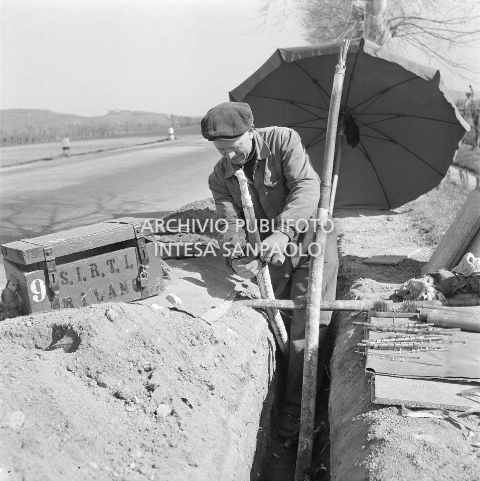 Operaio della SIRTI (Società Italiana Reti Telefoniche Interurbane) posa un cavo coassiale lungo la strada provinciale Verona-Soave