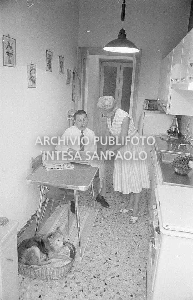 Il meccanico Giuseppe De Grandi, detto Pinella, ritratto insieme alla moglie nella cucina di casa; in basso a sinistra il cane nella sua cuccia