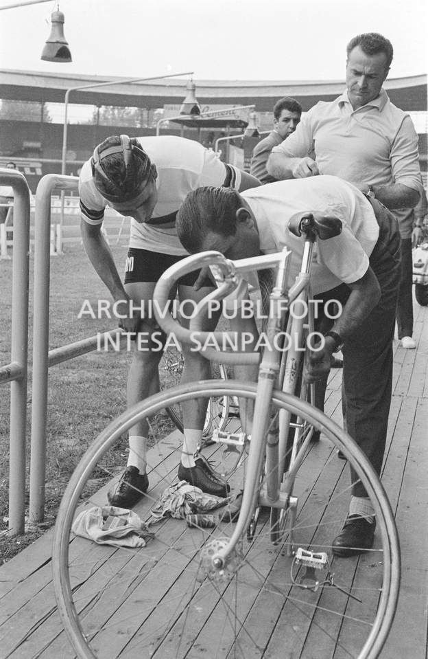Giuseppe De Grandi, detto Pinella, esegue gli ultimi controlli alla bicicletta che ha preparato per Roger Rivière, alle sua spalle, al velodromo Vigorelli di Milano