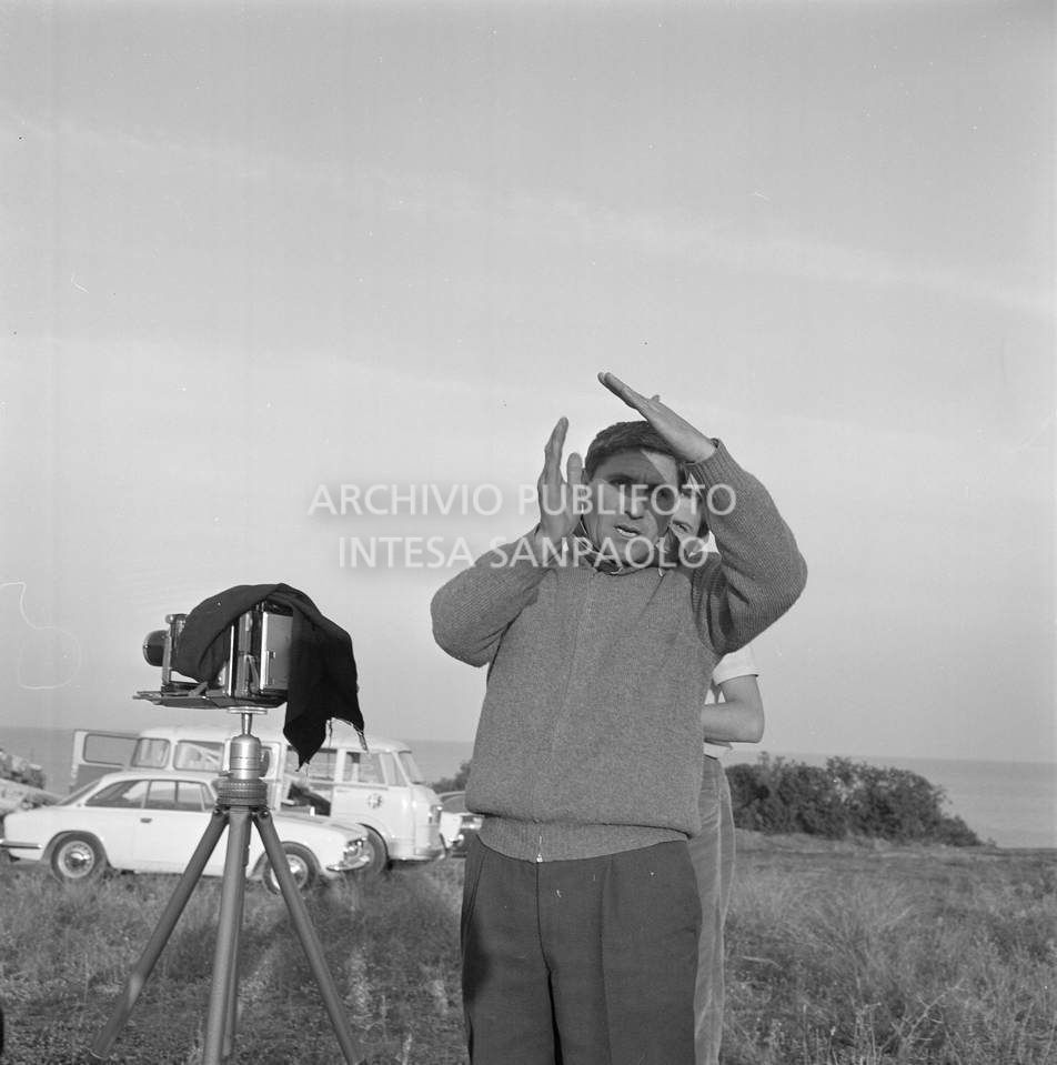Fotografo dell'agenzia Publifoto al lavoro sul Gargano: a fianco a lui una macchina fotografica su cavalletto