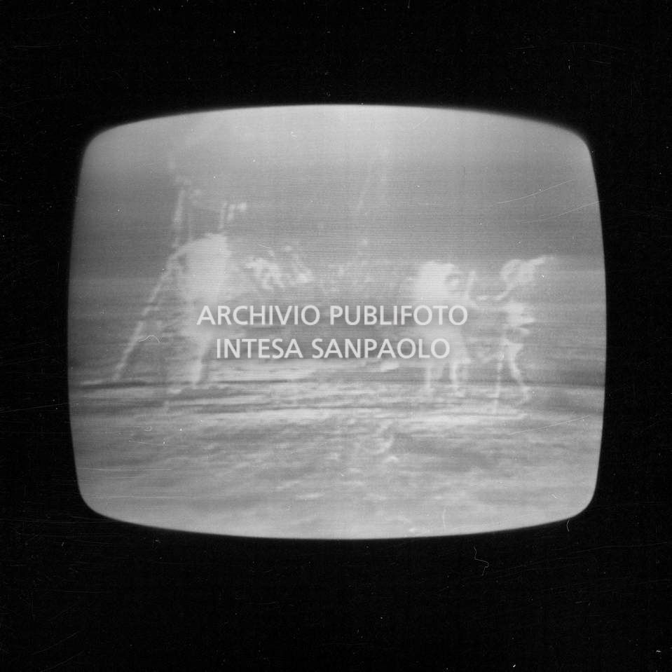 Ripresa dello schermo televisivo che trasmette la storica diretta dello sbarco sulla luna, durata 28 ore, e condotta dallo studio 3 della RAI di via Teulada a Roma qui in collegamento con lo studio di Milano: nell'immagine i primi passi sulla luna