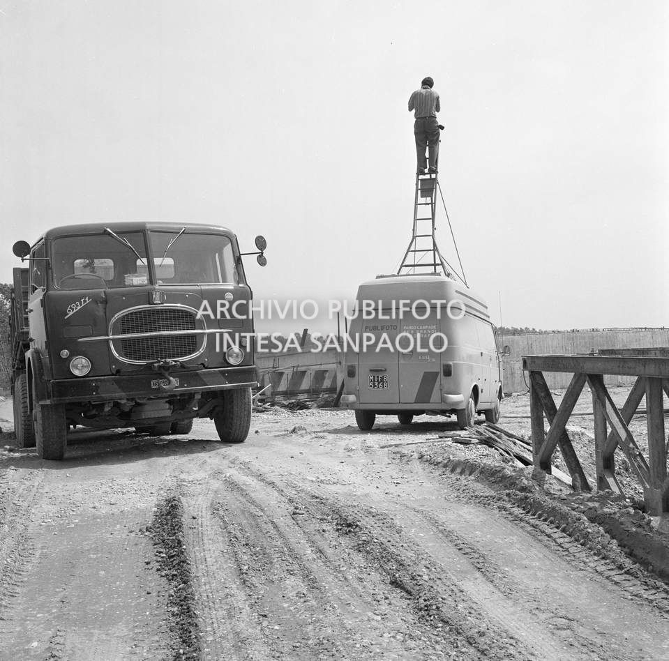 Un fotografo dell'agenzia Publifoto riprende da una scala montata sul tettuccio di un furgone Fiat 238 . A sinistra un autocarro Fiat 693 T1